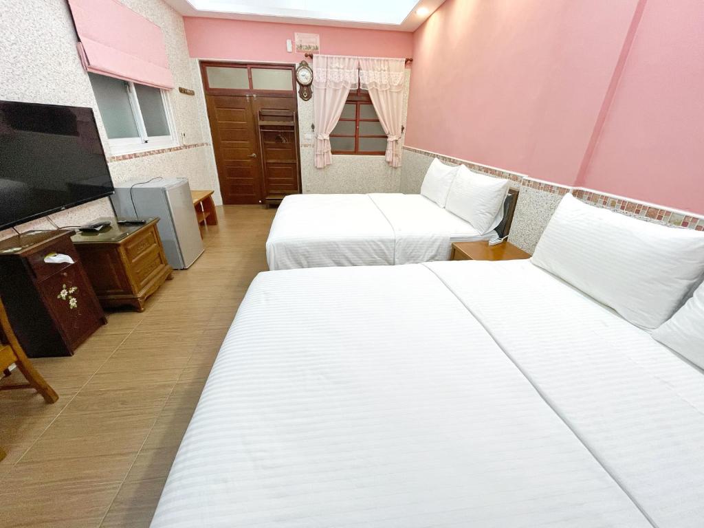 a hotel room with two beds and a tv at Yi-Shiou Home in Taitung City