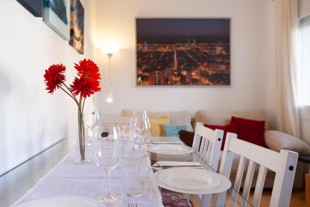巴塞隆納的住宿－Cute Apartment in Sants Station with HBO & Alexa & AC，餐桌,带玻璃杯和红花花瓶