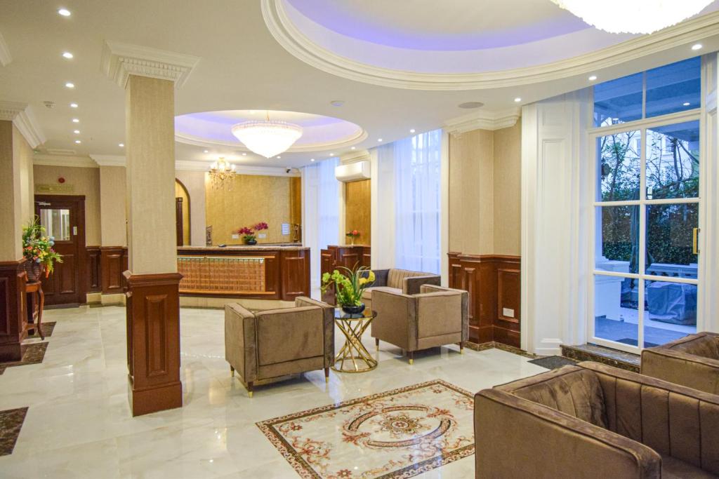 a lobby with couches and chairs in a building at Pembridge Palace Hotel in London