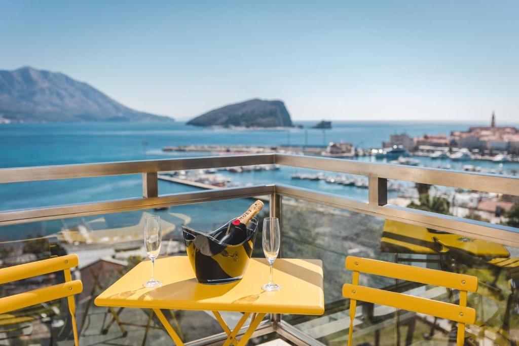einen Tisch mit Weinflaschen und Gläsern auf dem Balkon in der Unterkunft Fontana Residence Budva in Budva