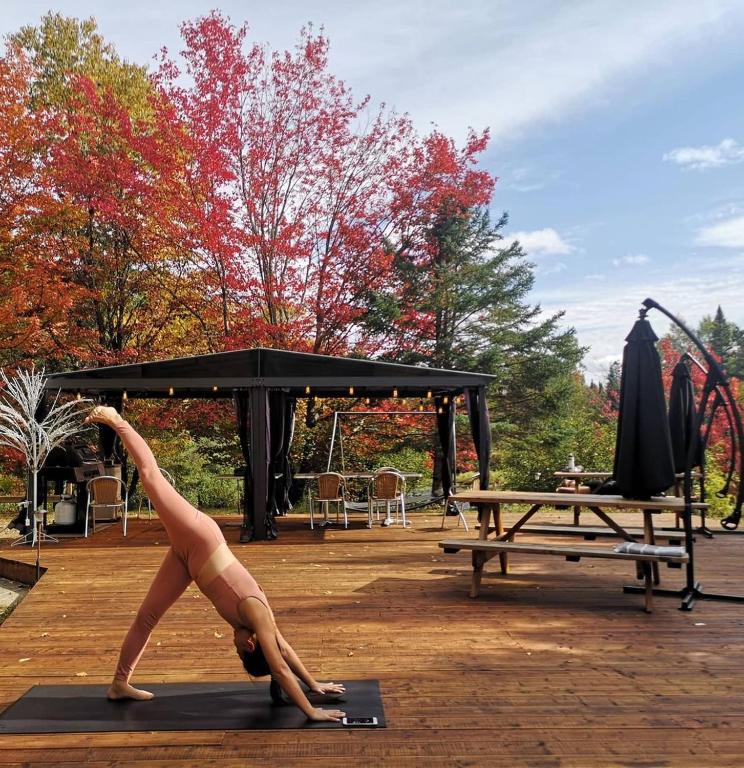 a woman doing a yoga pose in front of a picnic table at Oberge Inn Val-David in Val-David