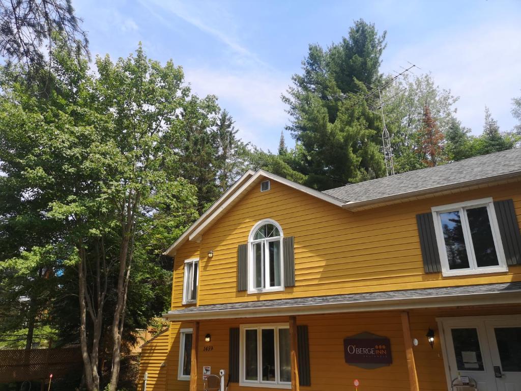 a yellow house with trees in the background at Oberge Inn Val-David in Val-David