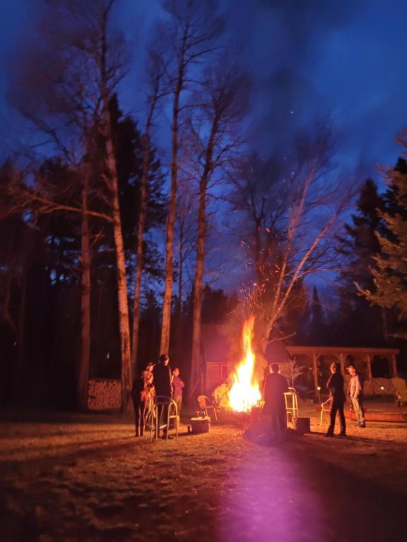 a group of people standing around a fire at night at Oberge Inn Val-David in Val-David