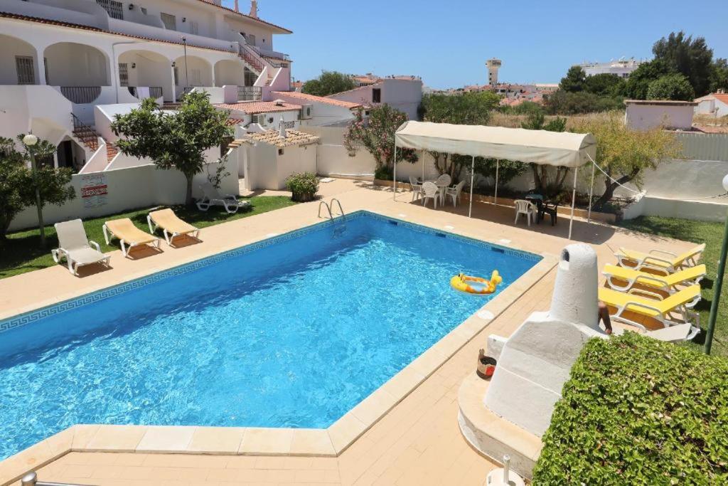 a swimming pool with chairs and a building at Apartamento V2 Pedro - By Bedzy in Albufeira
