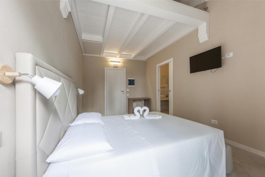 białe łóżko w pokoju z telewizorem w obiekcie Relais Borgo Camisa w mieście Castiadas