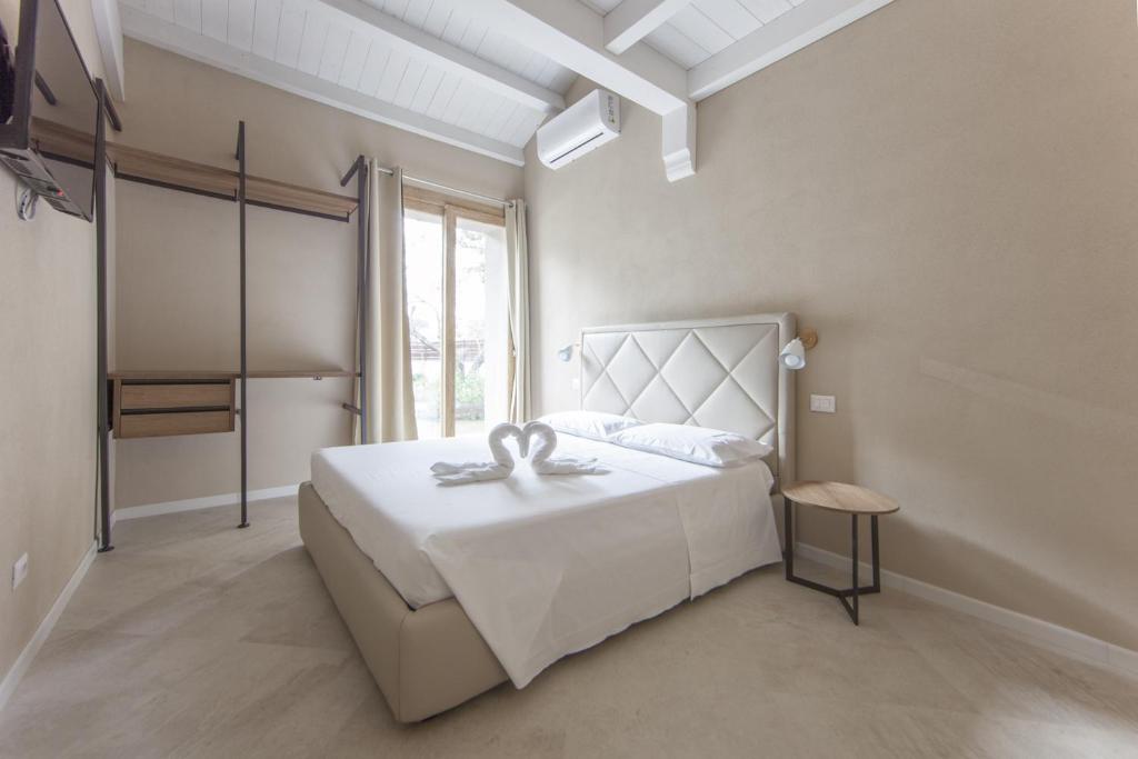 una camera da letto con un grande letto bianco con una grande finestra di Relais Borgo Camisa a Castiadas