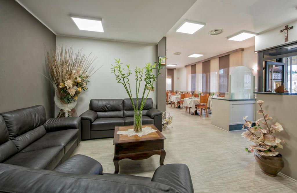 a living room with couches and a table with a vase at Hotel Candido in Diano Marina