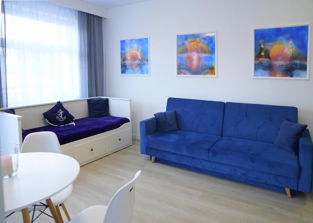 a living room with a blue couch and a table at Sea Family in Dziwnówek