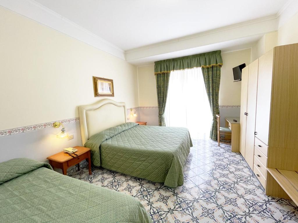 una camera d'albergo con due letti e una finestra di Hotel Reginella a SantʼAgata sui Due Golfi
