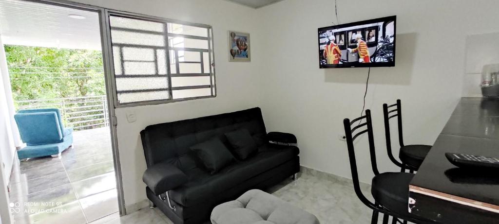 ein Wohnzimmer mit einem schwarzen Sofa und einem TV in der Unterkunft Hermoso apartamento in Florencia