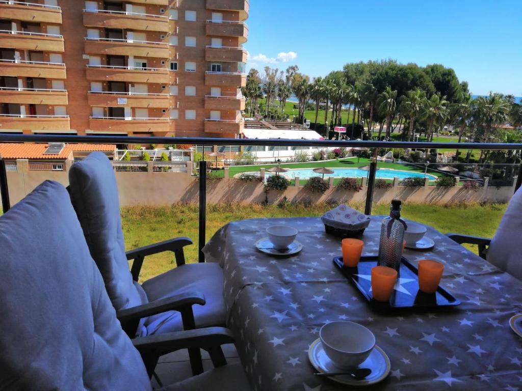 una mesa con una botella de vino en el balcón en APCOSTAS Marina D'or 1era línea - vista lateral mar, en Oropesa del Mar