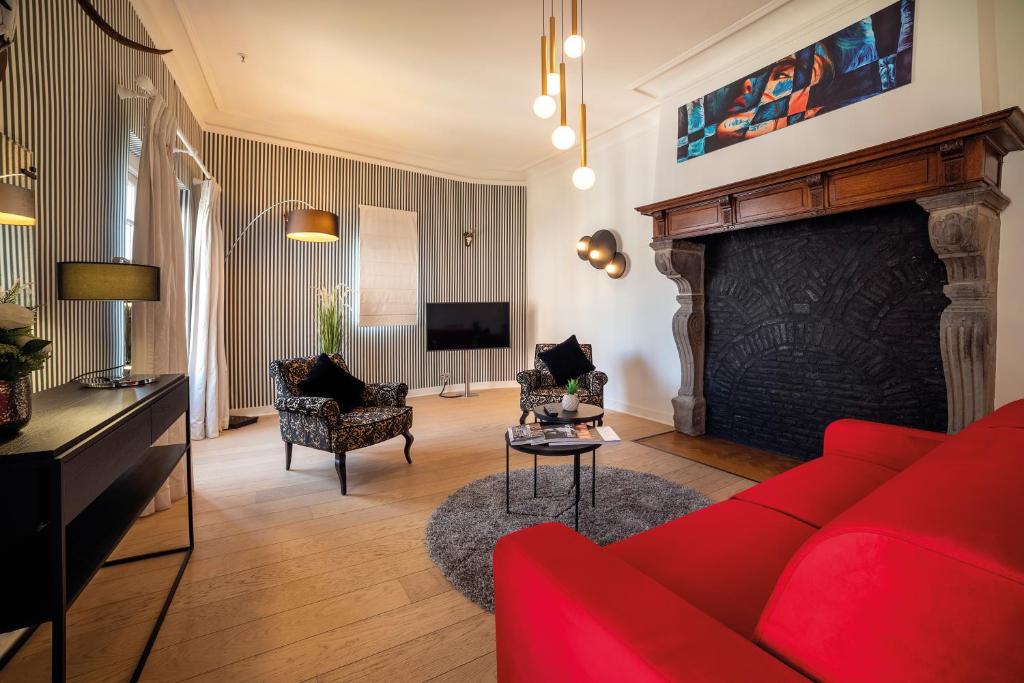 a living room with a red couch and a fireplace at Van Der Valk Sélys Liège Hotel &amp; Spa in Liège