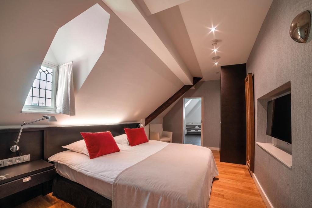 a bedroom with a large bed with red pillows at Van Der Valk Sélys Liège Hotel &amp; Spa in Liège