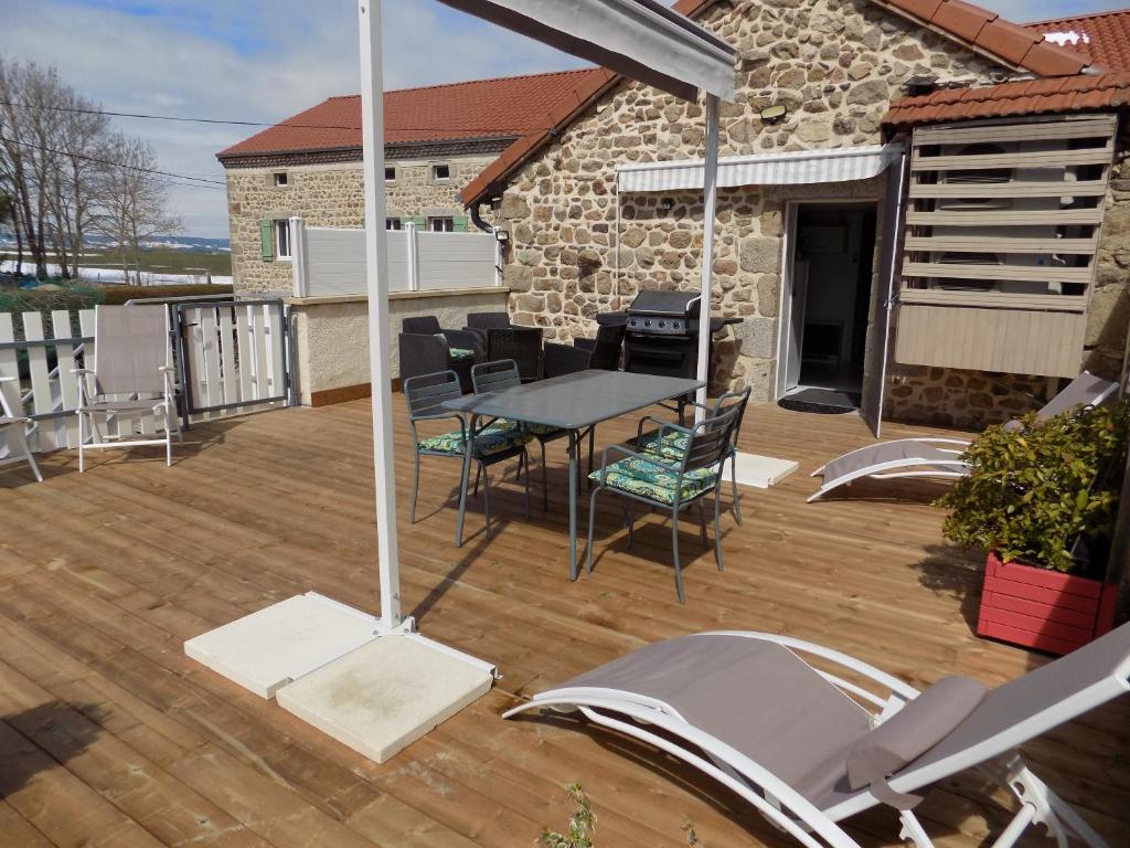 un patio con mesa y sillas en una terraza de madera en gite le peuplier, en Boisset