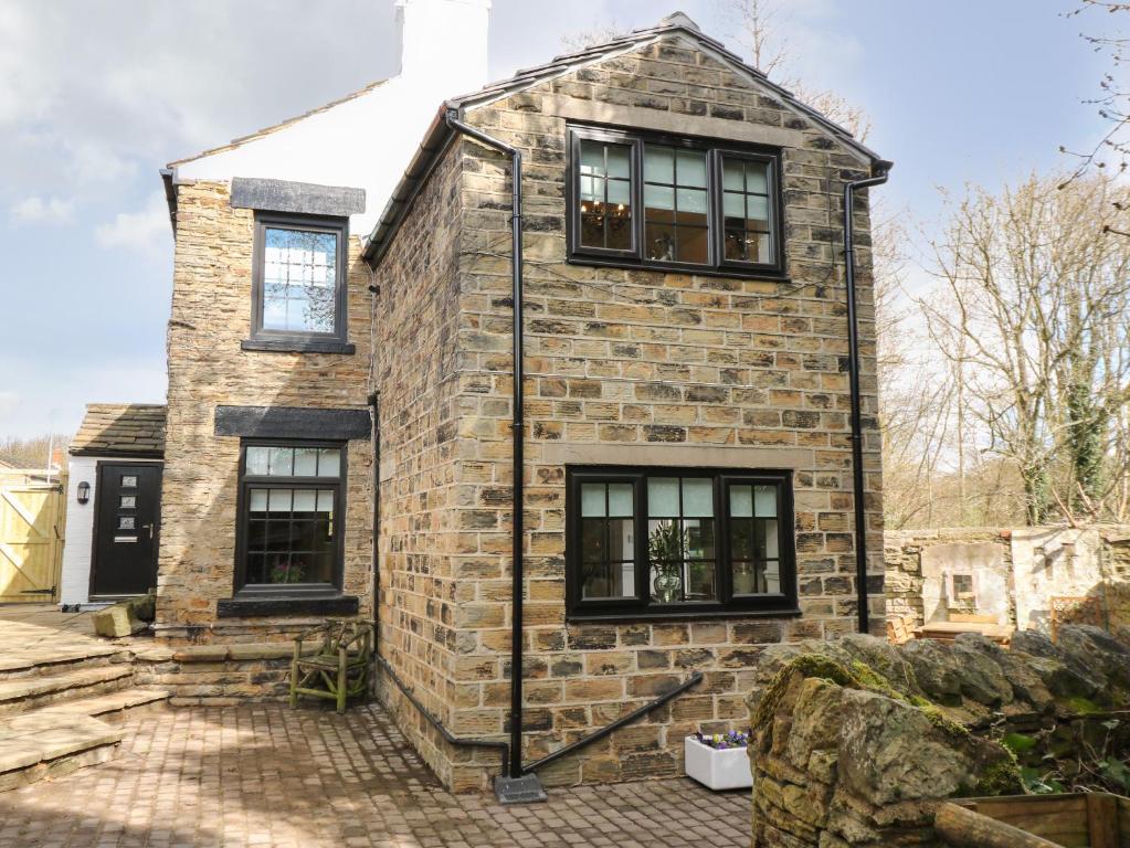 uma velha casa de tijolos com janelas pretas em The Cottage em Barnsley