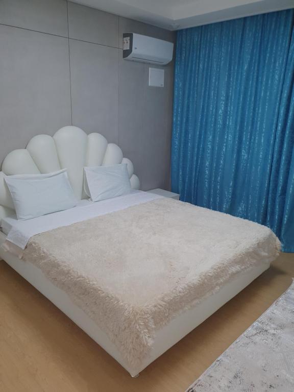 a bedroom with a white bed with a blue curtain at апартаменты в ЖК Хайвил in Astana