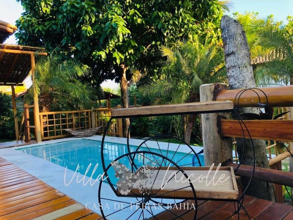 Villa Nicolle - Bahia - Praia do Espelho في برايا دو إسبيلهو: مسبح مع مقاعد بجانب سياج خشبي