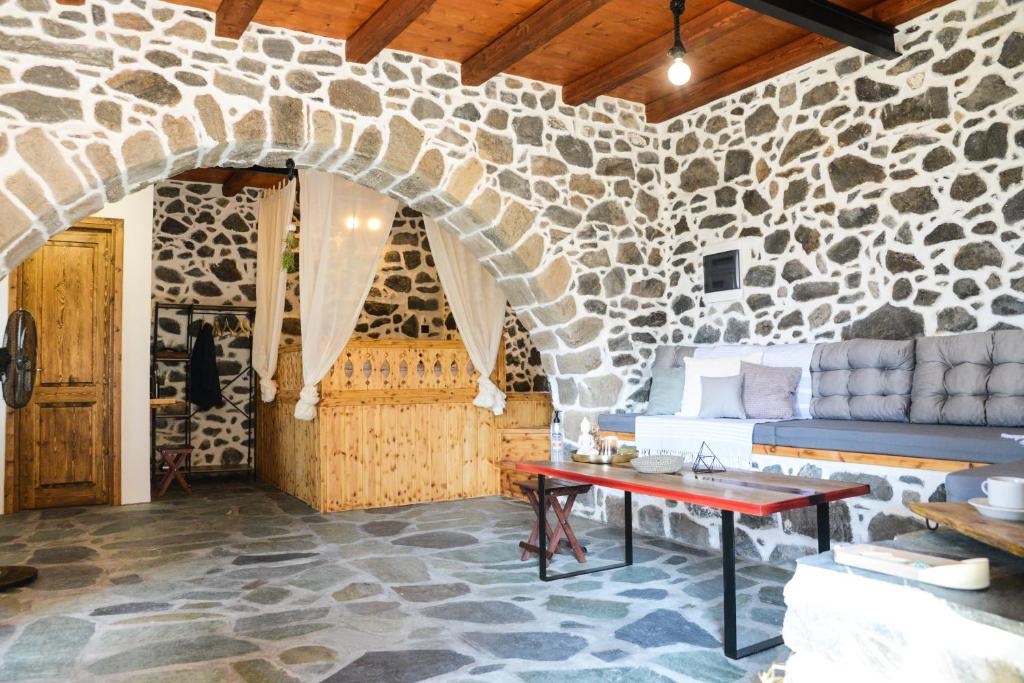 a living room with a stone wall and a table at Volcano View Nisyros in Emporeiós