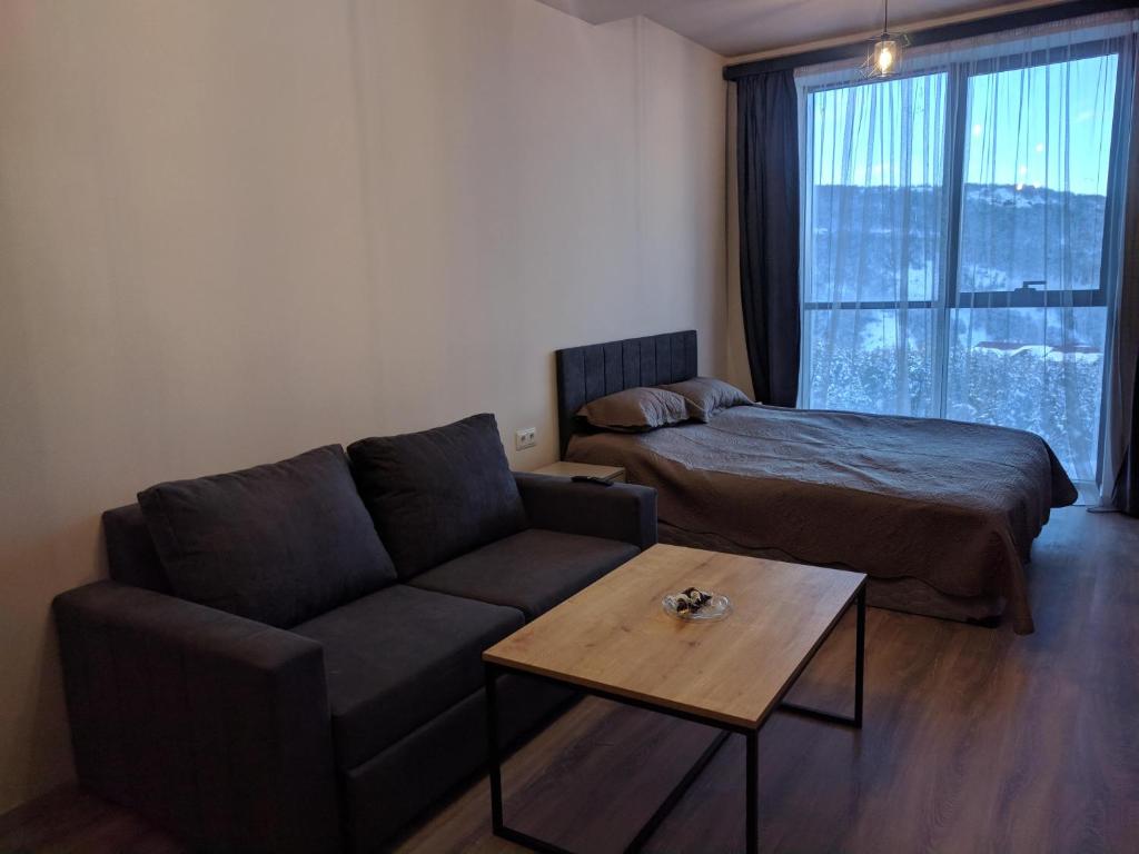 uma sala de estar com um sofá, uma cama e uma mesa em Lovely Aparthotel in Tsaghkadzor em Tsaghkadzor
