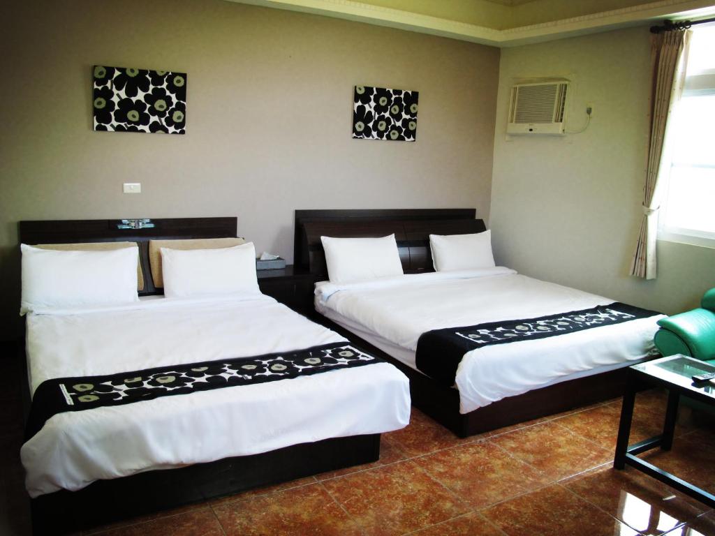 a room with two beds with white sheets at Camellia B&amp;B in Taitung City