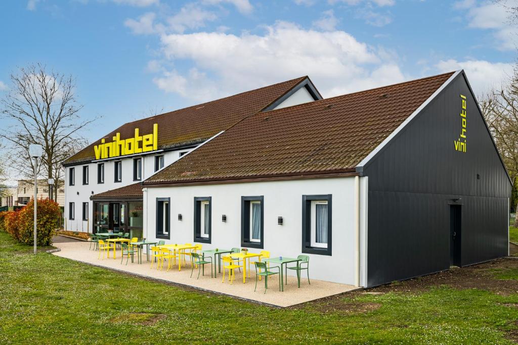 a building with tables and chairs in front of it at Vini Hotel in Beaune