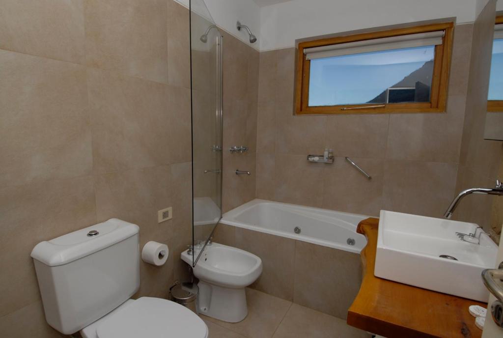 a bathroom with a toilet and a tub and a sink at Galileo Boutique Hotel in San Carlos de Bariloche