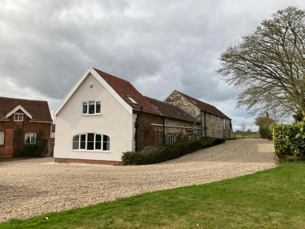 a house on a gravel road next to two buildings at May Cottage in Bridlington