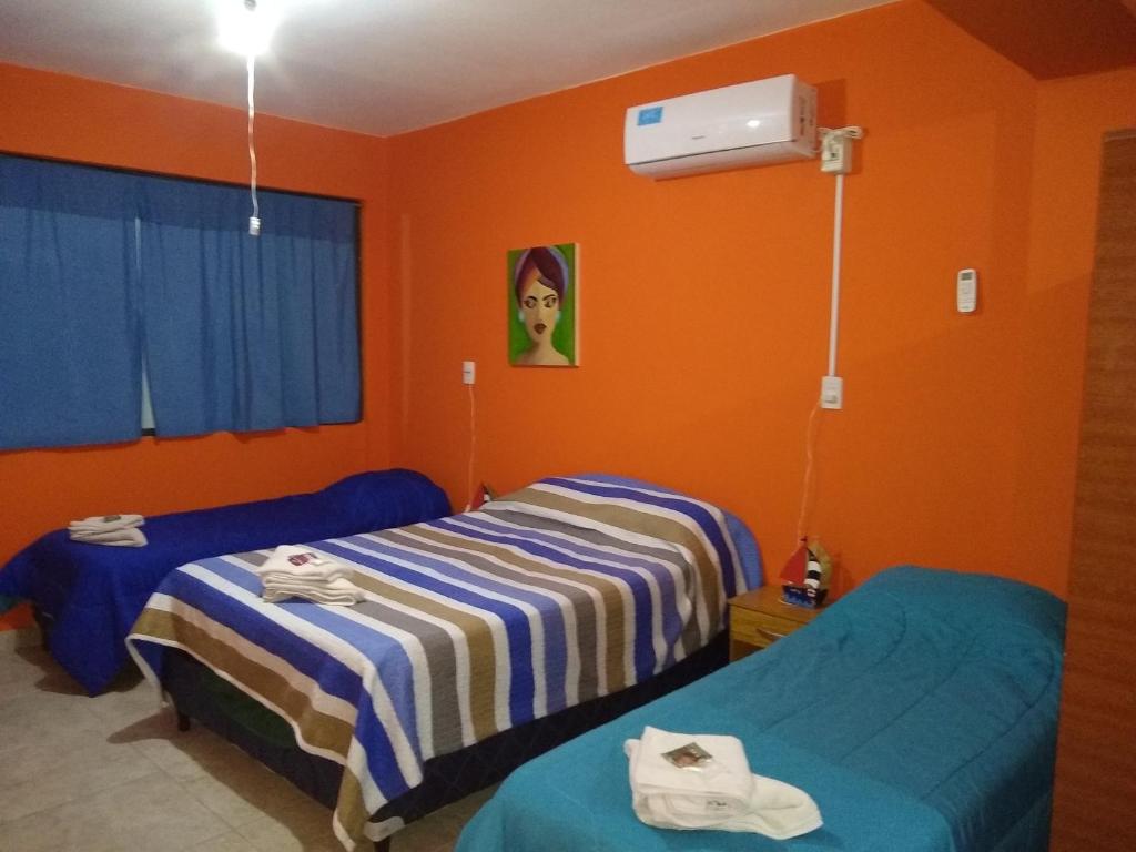 two beds in a room with orange walls at Norte Alojamiento in Belén