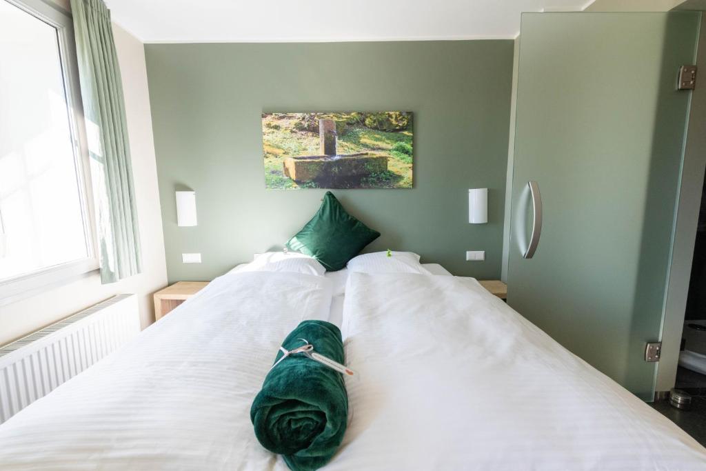 a bedroom with two white beds with green pillows at Feuerhardt in Feuerscheid