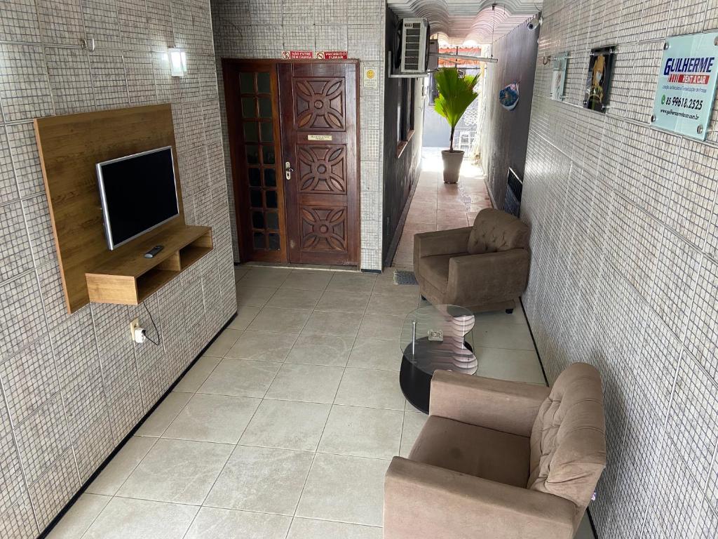 - un salon avec une télévision, un canapé et des chaises dans l'établissement Guilherme Hostel, à Fortaleza