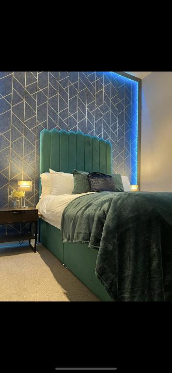 a bedroom with a green bed with a blue headboard at The Law House By The Opulence - Free City Centre Parking in Bradford