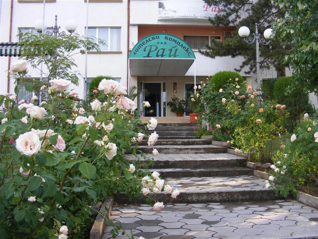a set of stairs in front of a building with roses at Paradise Hotel in Madzharovo