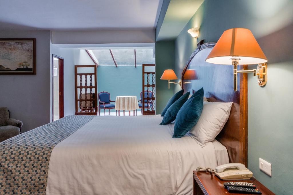 Un dormitorio con una cama y un teléfono en una mesa. en Hotel Libertador, en Loja