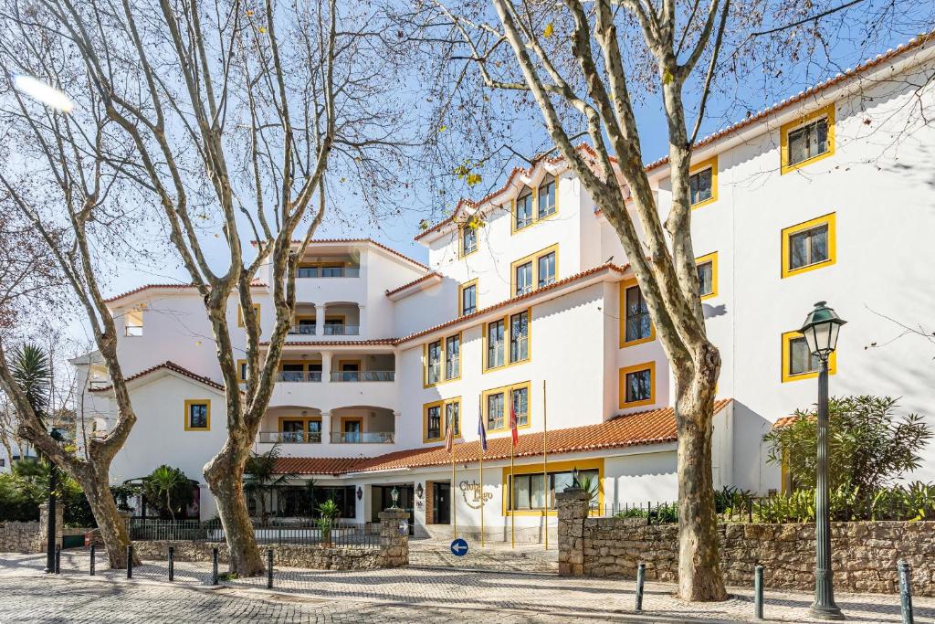 a large white building with trees in front of it at Clube do Lago Hotel in Estoril