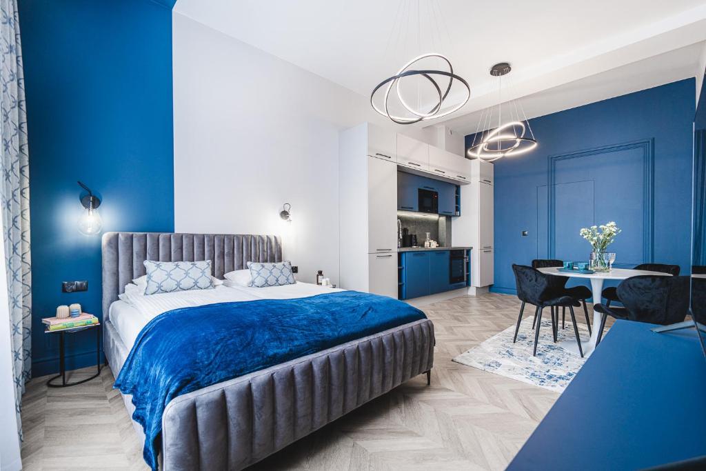 a blue and white bedroom with a bed and a table at Apartament 21A- Hvile Stay in Toruń