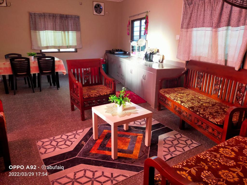 sala de estar con sillas rojas y mesa en Ulya Homestay 3, en Jertih