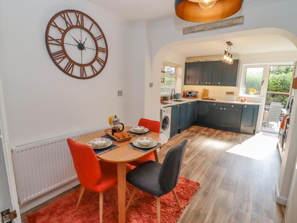 una cocina con mesa y sillas y un reloj en la pared en Robellen Corner, en Banbury