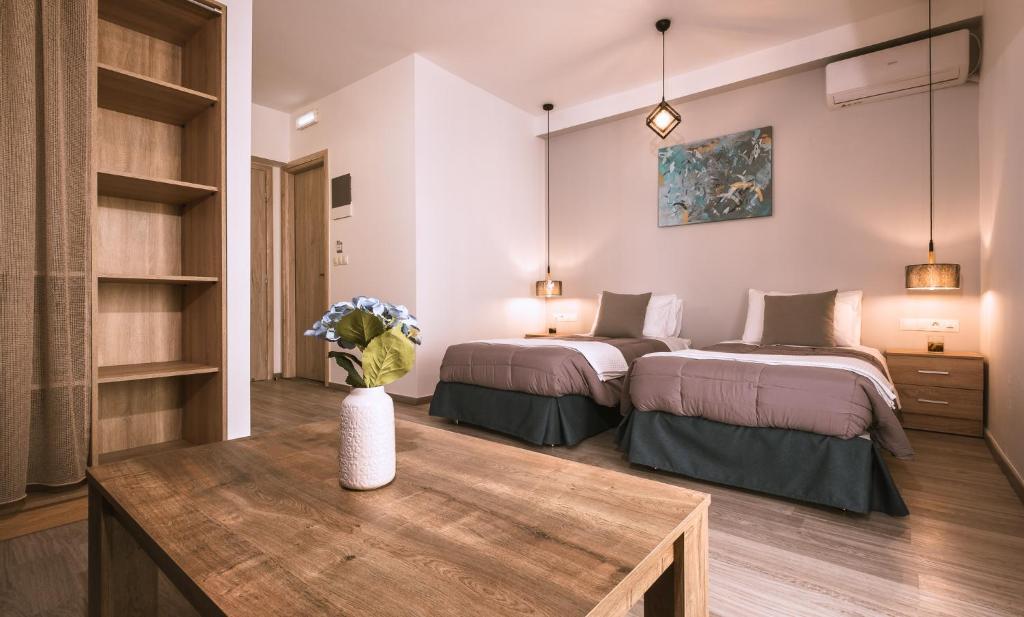 a bedroom with two beds and a wooden table at Sophies Greek Gateway in Kardamaina
