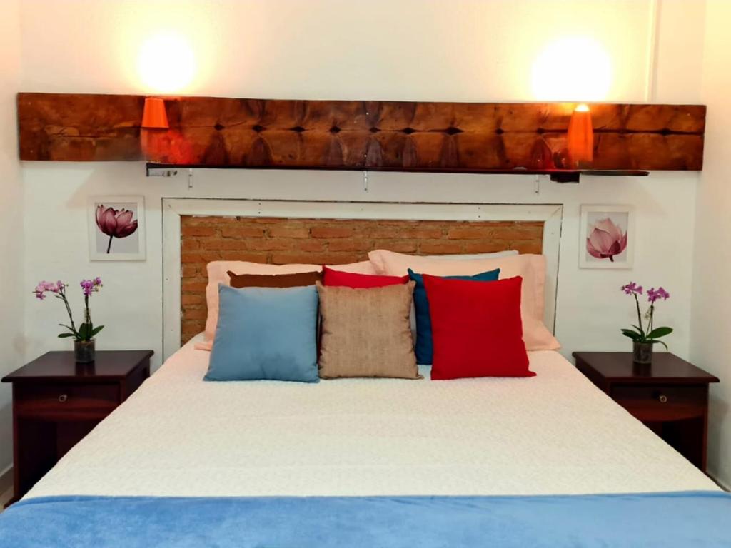 um quarto com uma cama com almofadas vermelhas e azuis em Casa caiçara na Vila - Casa 01- Hospedaria da Vila em Ilhabela