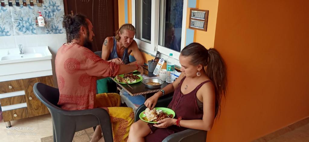Rudransh home stay في ريشيكيش: مجموعة من الناس يجلسون حول طاولة يأكلون الطعام