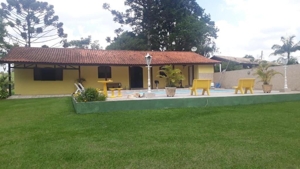 a yellow house with yellow chairs in a yard at Sítio Toa Toa in São Roque