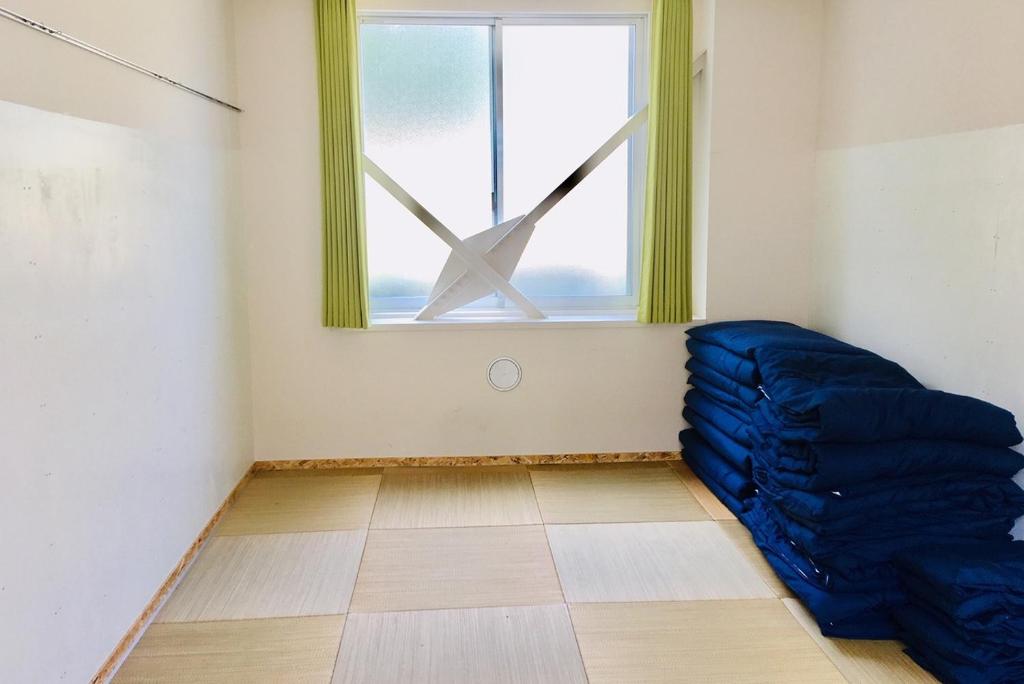 Agri Museum NADA - Vacation STAY 98172v في Minamiawaji: غرفة بها حقيبة نوم زرقاء أمام النافذة