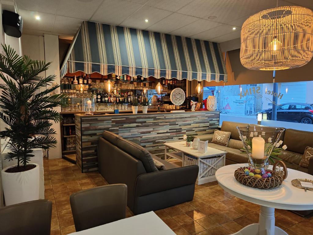 a restaurant with a bar with couches and a table at Hotel Sfinx in De Panne