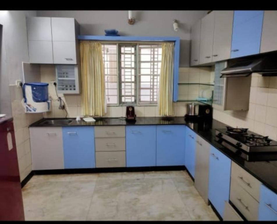 een grote keuken met witte kasten en een raam bij PRAVESH VILLA in Pondicherry