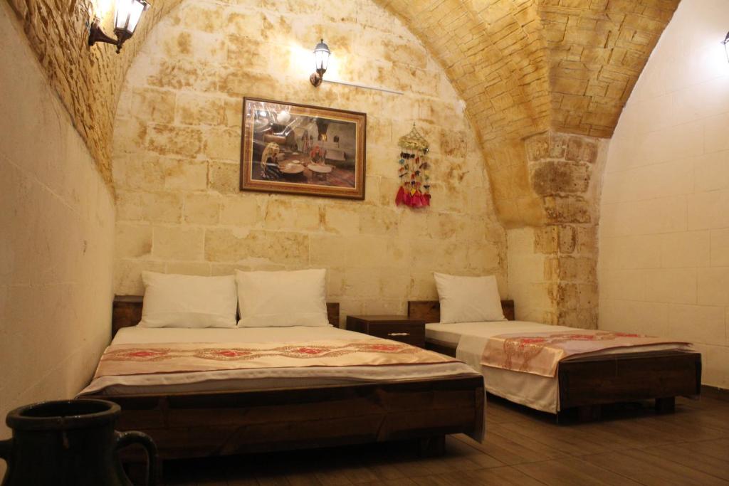 a bedroom with two beds in a stone wall at Grand Babil Otel in Sanlıurfa