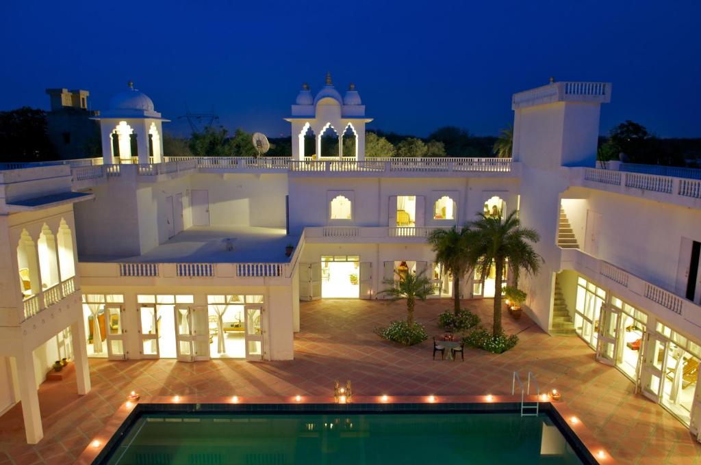 a large white mansion with a swimming pool at night at Savista Retreat in Jaipur