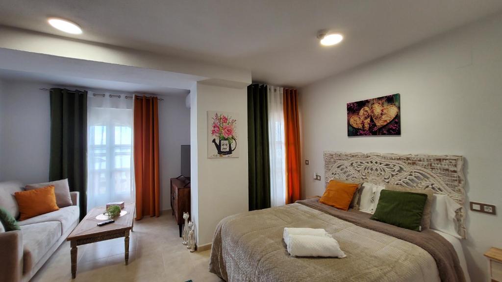 a bedroom with a large bed and a couch at Estudios Costavigía Mazagón by Ramona in Mazagón