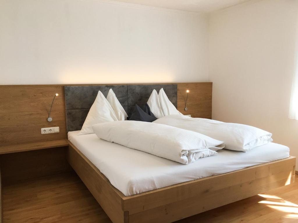 Una cama con sábanas blancas y almohadas. en Knirschenhof, en Windischgarsten
