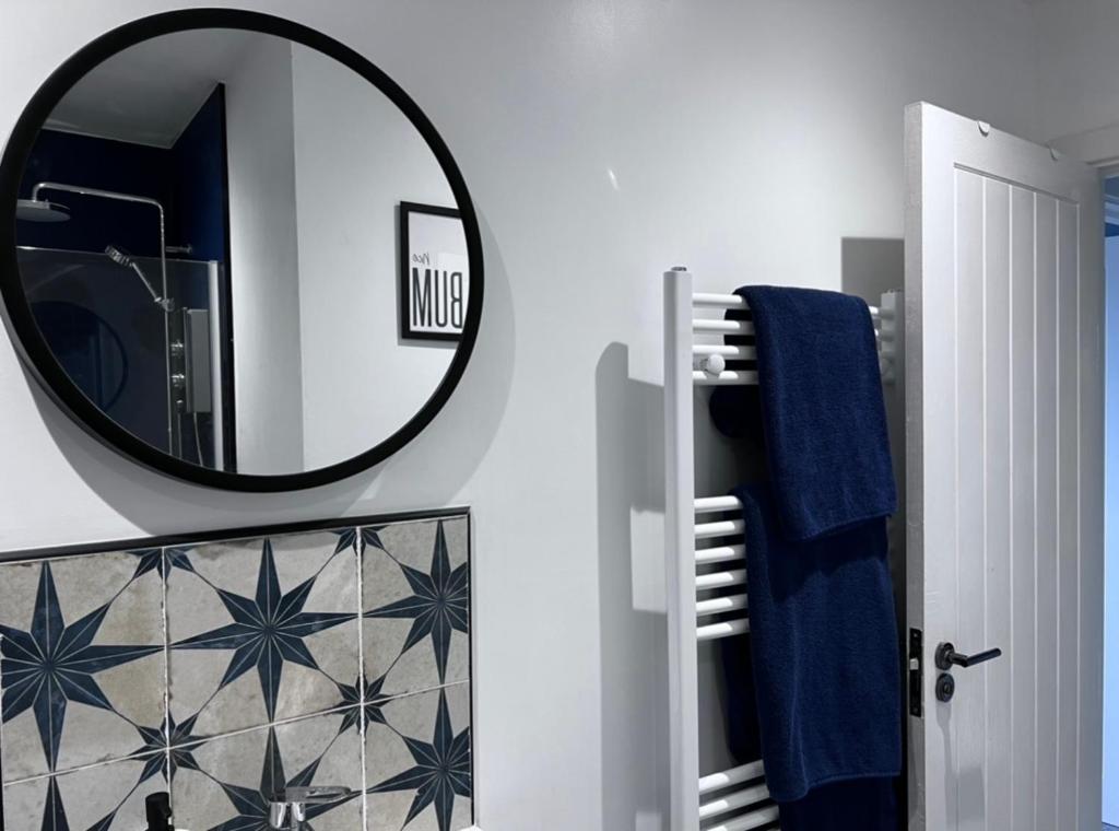 a bathroom with a mirror and a blue towel at Orchard Lodge -Coastal Retreat, new build, village views, private garden and terrace in Saint Brides Major