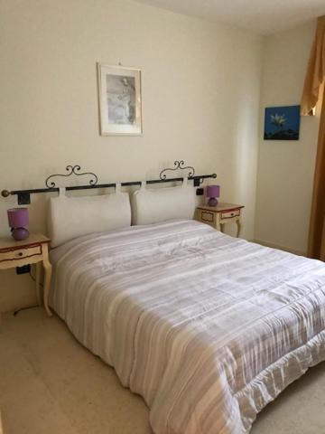 sypialnia z dużym białym łóżkiem z dwoma stołami w obiekcie Appartamento Du Lac 2 w mieście Desenzano del Garda